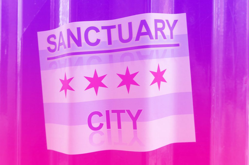 Sanctuary City written on a Chicago flag